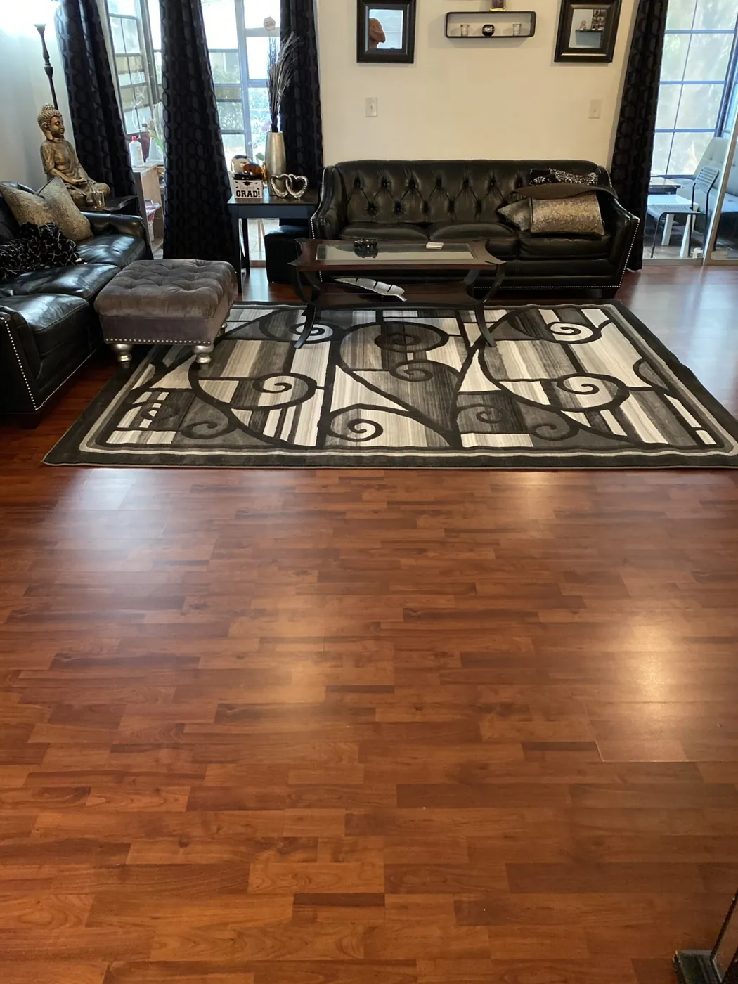 Living room with polished wood floors, a leather sofa and a patterned rug