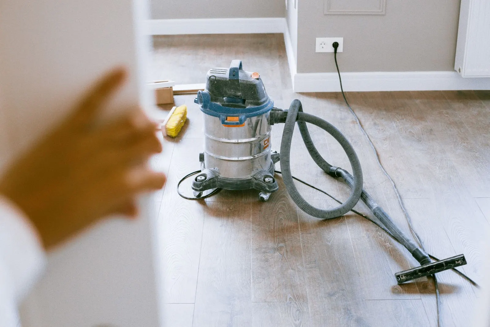 A shop vacuum on a newly laid wood floor in a renovated room